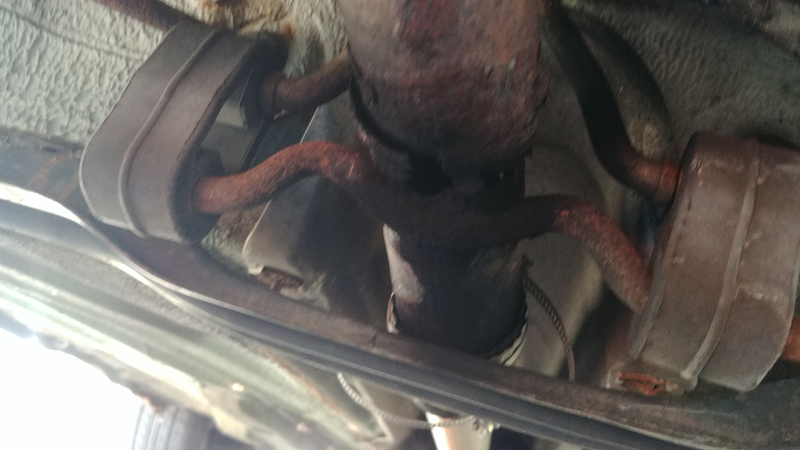 On the crossmember in front of the wheels. It isn’t supposed to even sit on that. You can see my longest lasting patch in the back.